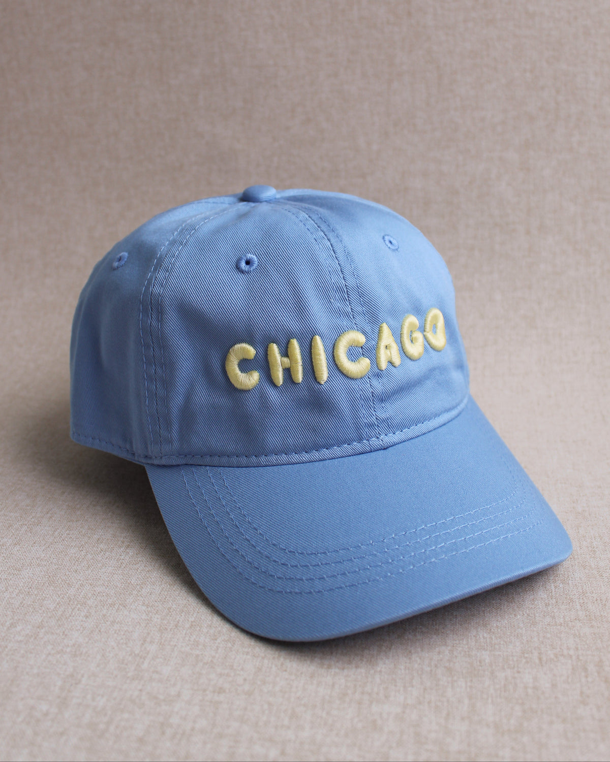 Blue cap with 'CHICAGO' embroidered on it against a beige background